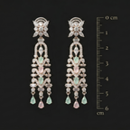 Pair of elegant earrings with green gemstones and a ruler for scale on a black background