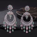 Pair of ornate earrings with gemstones on a dark surface