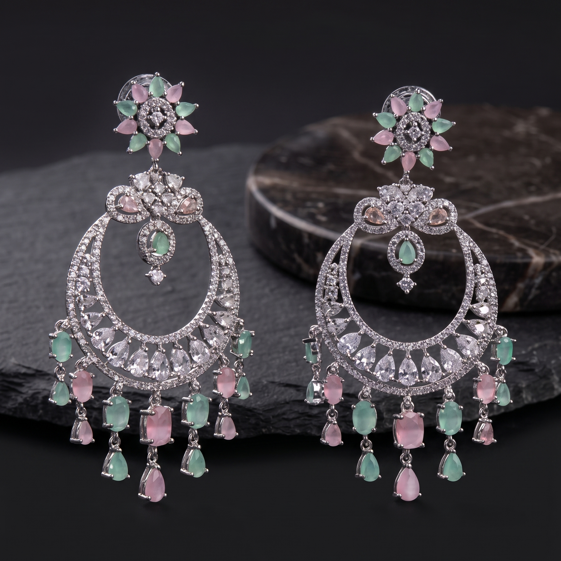 Pair of ornate earrings with gemstones on a dark surface