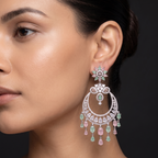 Close-up of a woman wearing a pair of ornate earrings with gemstones on a dark background