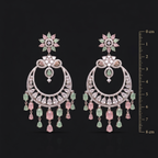 Pair of ornate earrings with gemstones on a black background, accompanied by a measurement scale.