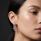 Close-up of a woman wearing a silver earring against a dark background