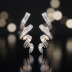 Pair of silver earrings with diamond accents on a reflective surface with blurred lights in the background