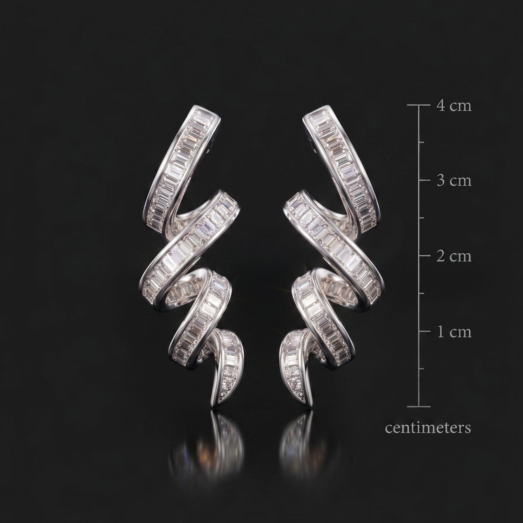 Pair of silver earrings with clear stones on a black background with measurement scale.