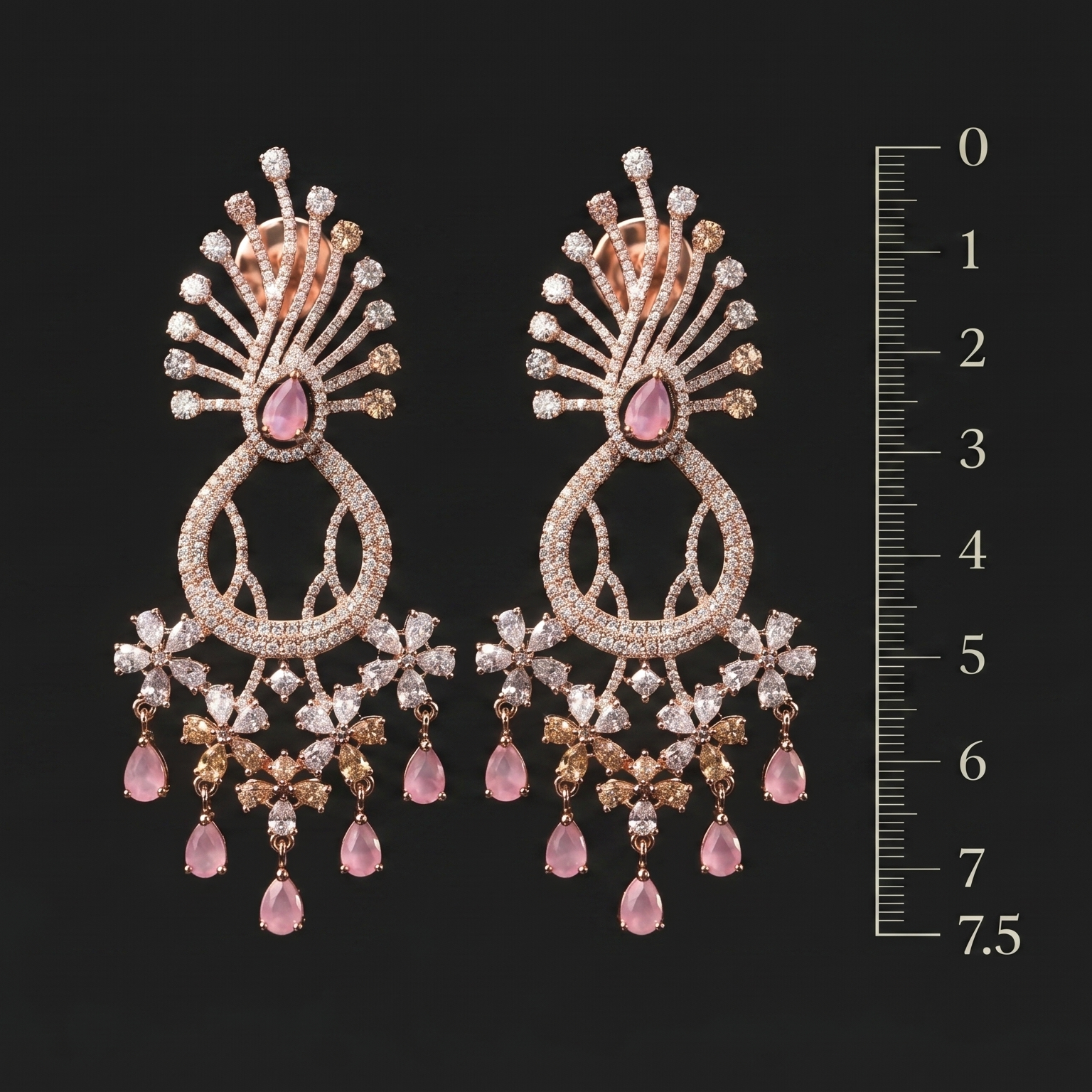 Pair of ornate earrings with pink gemstones and a scale for size reference on a black background.