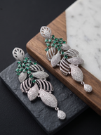 Pair of silver earrings with green gemstones on a dark surface
