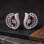 Pair of silver earrings with purple gemstones on a dark surface