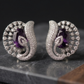 Silver earrings with purple gemstones on a dark surface