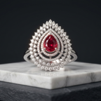 Elegant ring with a red gemstone on a marble stand against a black background