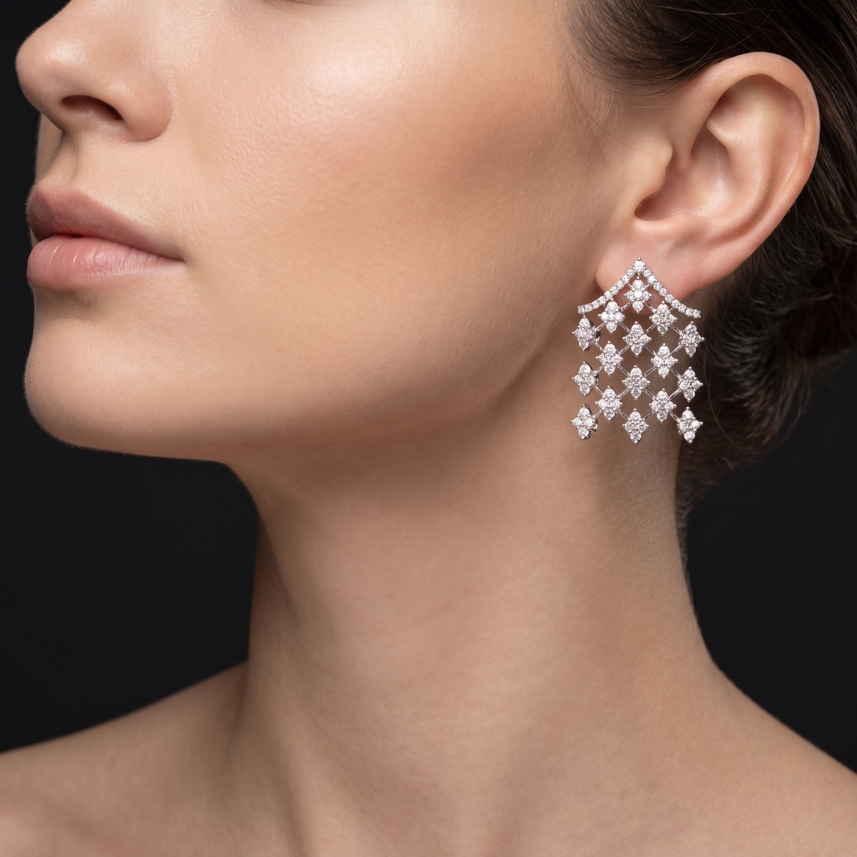 Close-up of a woman wearing diamond earrings with a black background