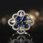 Elegant ring with blue gemstone and diamond accents on a reflective surface with a dark background