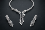 Silver necklace and earrings set on a dark textured background