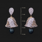 Ornate earrings with black beads and measurement scale on a dark background