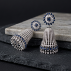 Silver jhumka earrings with blue gemstones on a dark surface