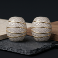 Pair of silver and gold earrings on a dark surface with a black background