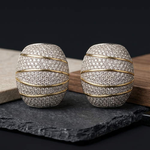 Pair of silver and gold earrings on a dark surface with a black background