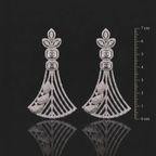 Pair of ornate silver earrings with gemstones on a black background with a scale for size reference.