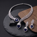 Jewelry set with necklace and earrings featuring blue gemstones on a dark surface.