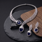 Jewelry set with necklace and earrings featuring blue gemstones on a dark surface.
