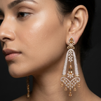 Close-up of a woman wearing elegant gold and diamond earrings against a dark background