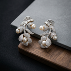 Pair of ornate earrings with pearls on a dark surface