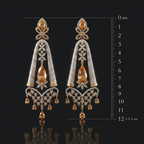 Pair of gold and diamond earrings with a measurement scale on a black background