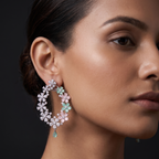 Close-up of a woman wearing floral hoop earrings against a dark background