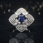 Diamond ring with a blue gemstone on a reflective black surface