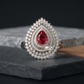 Teardrop-shaped ring with a red gemstone on a dark surface