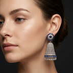 Close-up of a woman wearing a pair of dangling earrings with blue and clear gemstones.