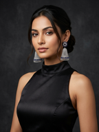 Woman wearing a black dress and large earrings against a dark background