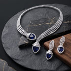 Silver necklace and earrings with blue gemstones on a dark surface