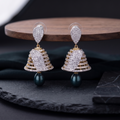 Pair of gold and diamond earrings on a dark surface with a wooden platform