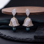 Pair of gold and diamond earrings on a dark surface with a wooden platform