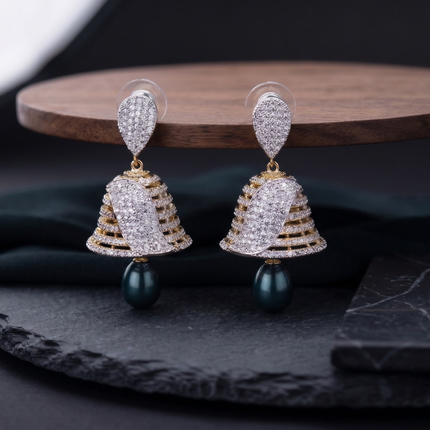 Pair of gold and diamond earrings on a dark surface with a wooden platform