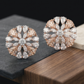 Pair of rose gold and diamond earrings on a dark surface