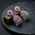 Pair of earrings with pink gemstones on a dark surface