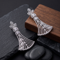 Silver earrings on a dark surface with a wooden block