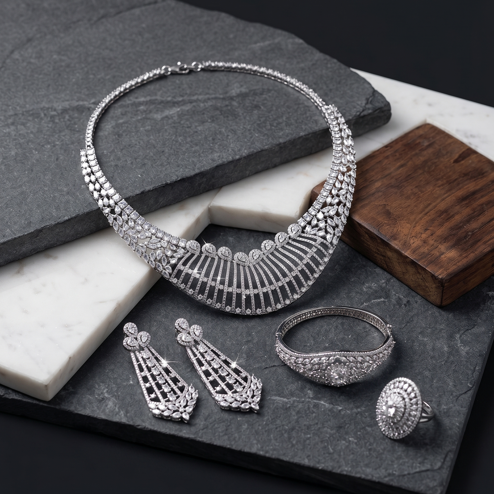 Silver jewelry set including necklace, earrings, bracelet, and ring on a dark surface.