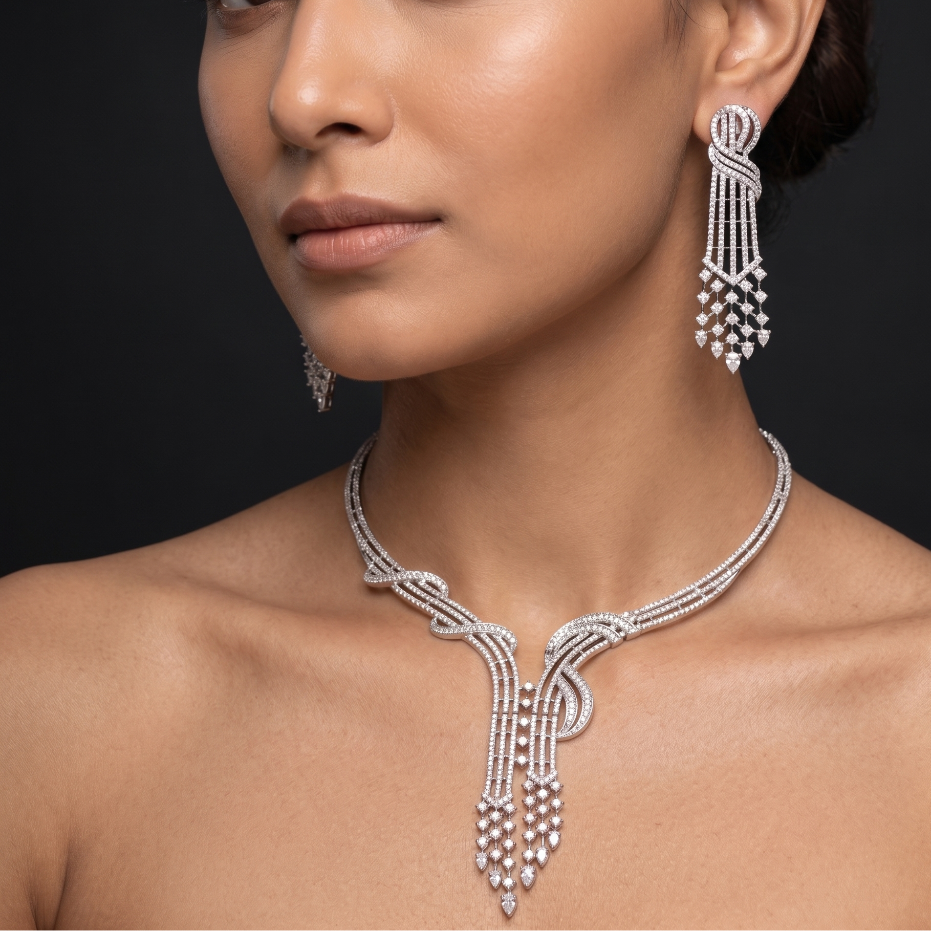 Woman wearing a silver necklace and earrings against a black background