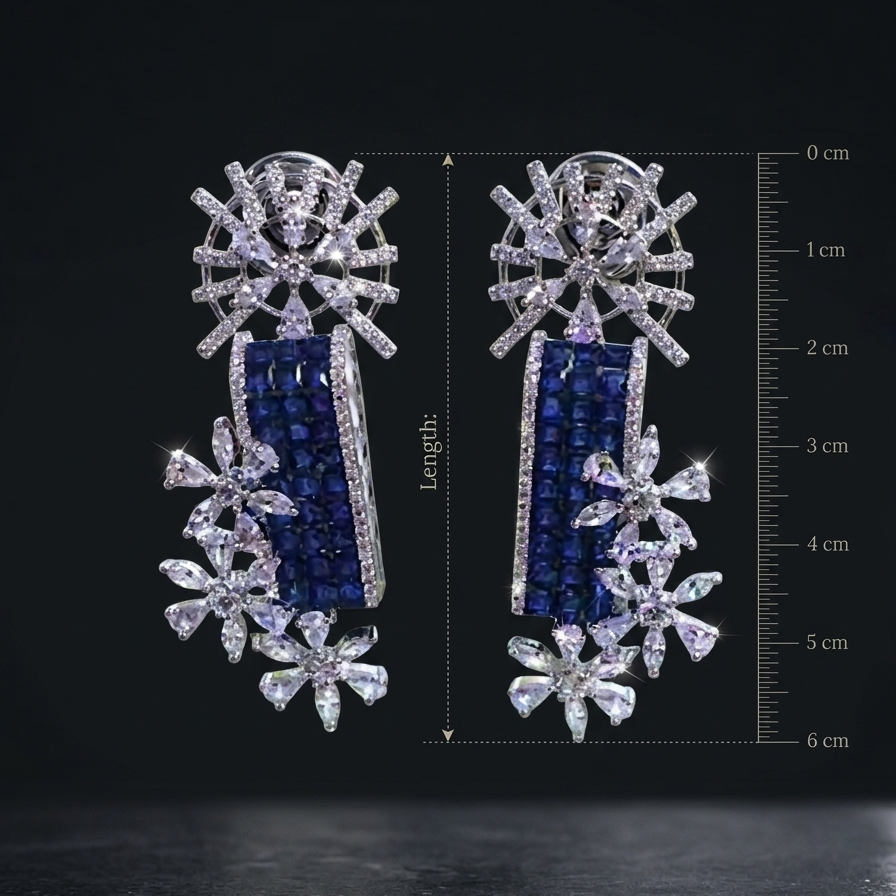 Pair of silver earrings with blue and clear gemstones, shown with a measurement scale on a black background.