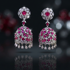 Pair of ornate earrings with pink gemstones and reflective surface