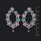 Pair of floral earrings with gemstones on a black background, accompanied by a ruler for scale.