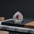 Elegant ring with a red gemstone and diamond accents on a dark surface.