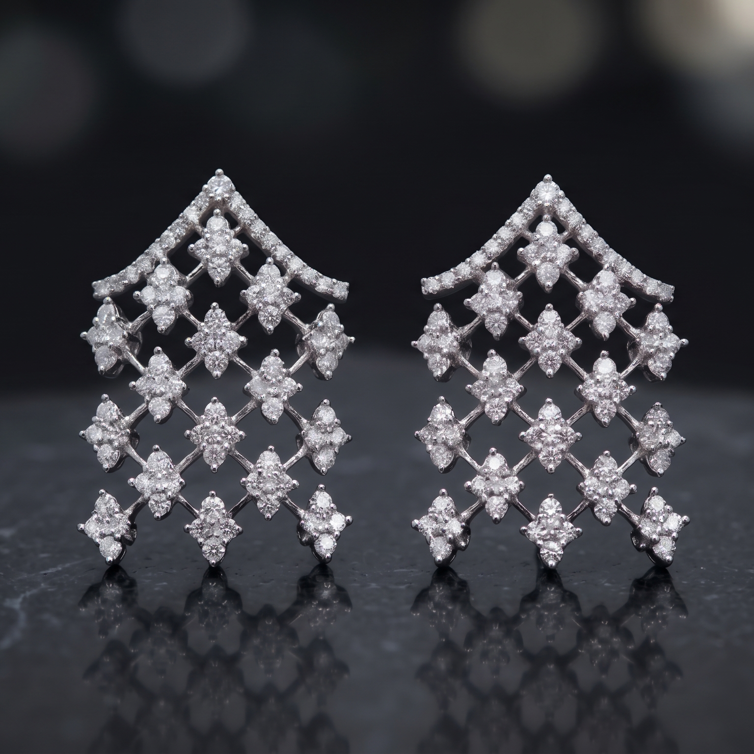 Pair of diamond earrings on a dark reflective surface with a blurred background