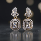 Pair of diamond earrings on a reflective surface with a blurred background