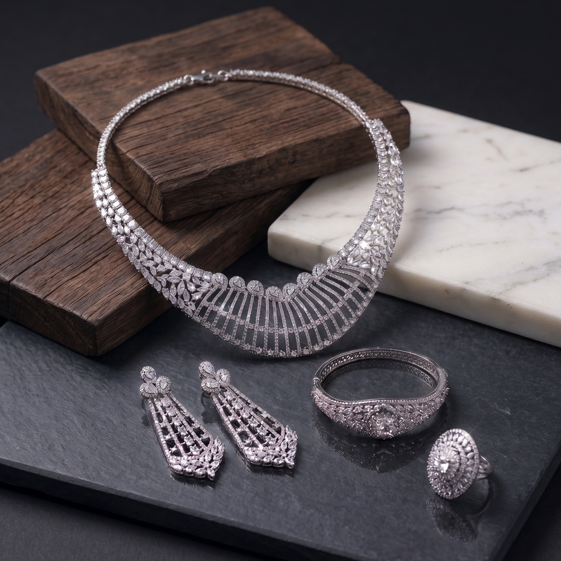 Silver jewelry set including necklace, earrings, and rings on a dark surface with a wooden block and marble piece.