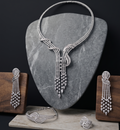 Silver jewelry set including necklace, earrings, bracelet, and ring on a dark background