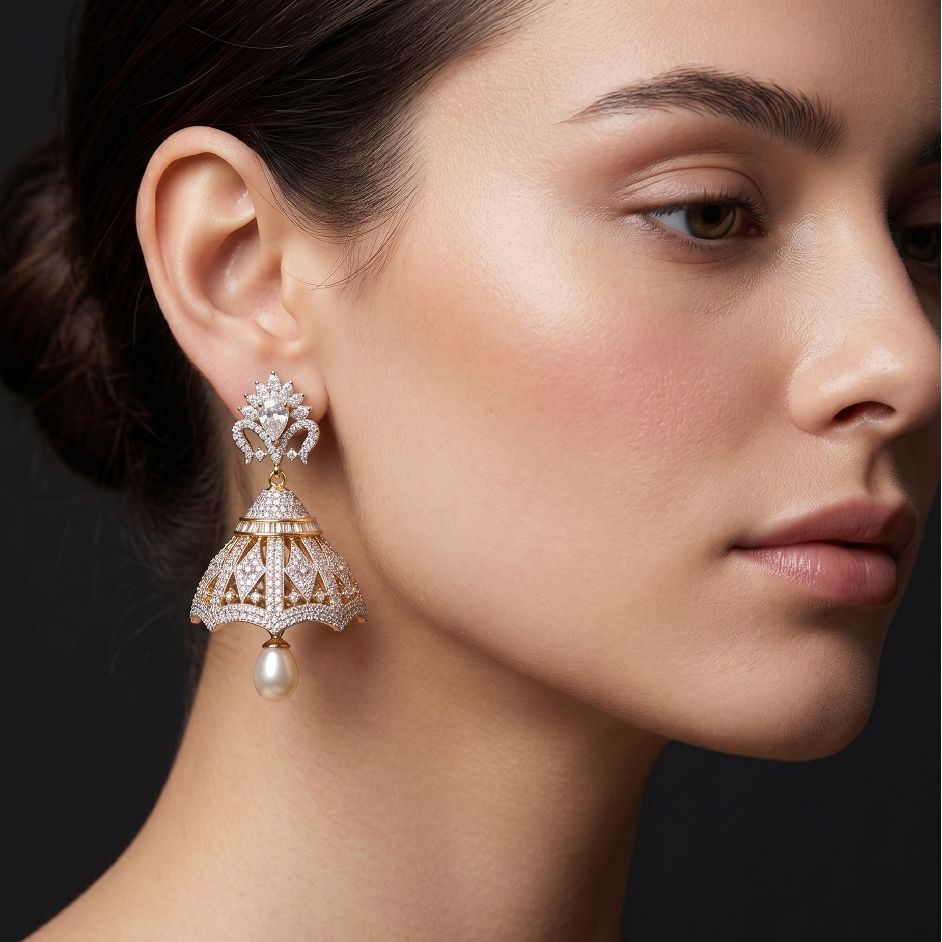 Close-up of a woman wearing a diamond earring with a pearl drop on a dark background