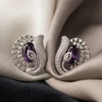 Pair of silver earrings with purple gemstones on a soft fabric background